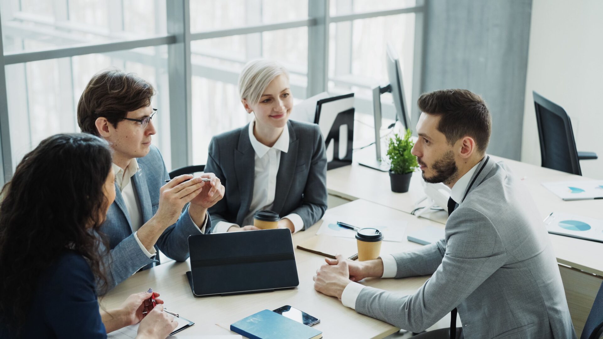 Group of professionals having a discussion in a modern office setting with natural light.